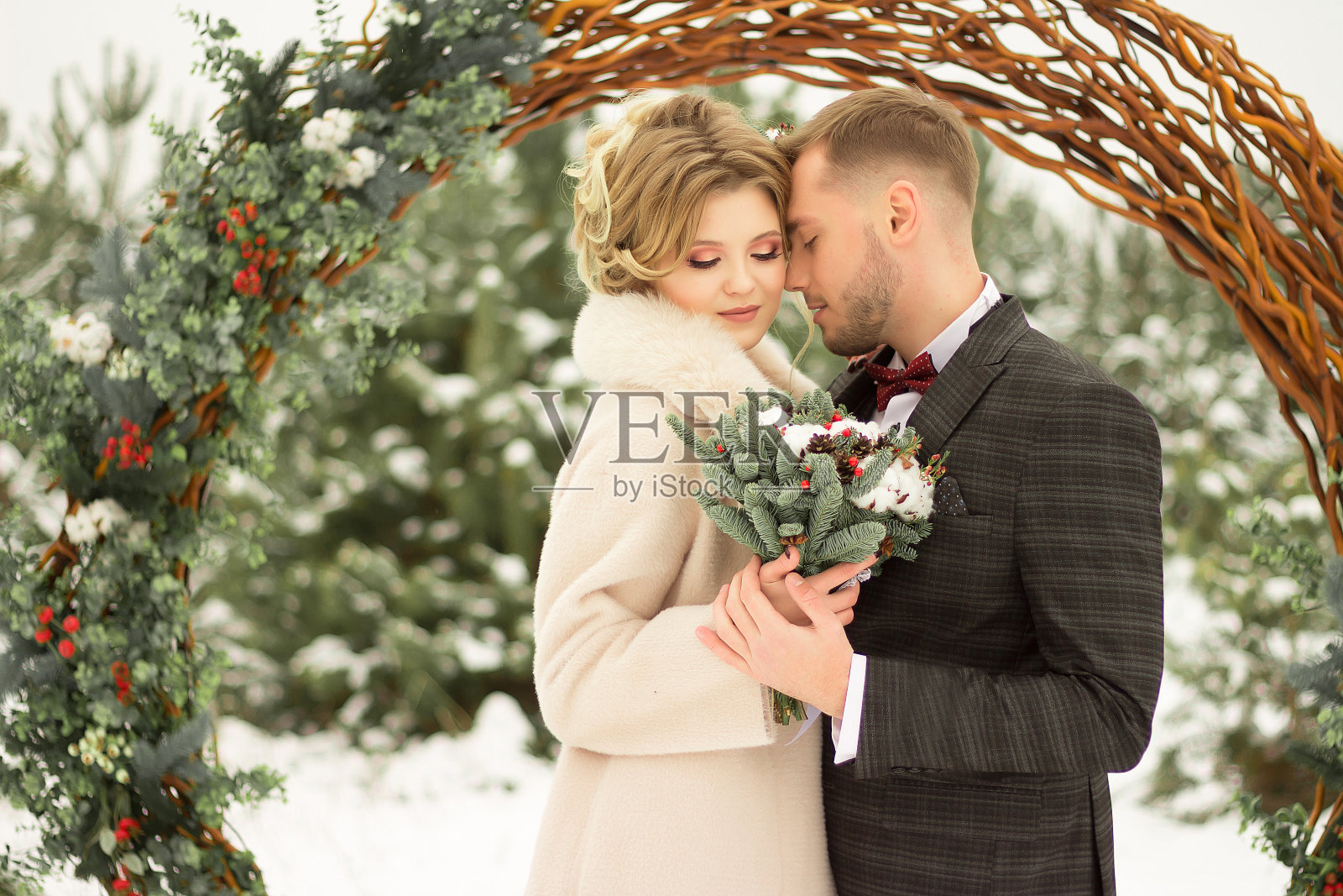 这对情侣拥抱着，亲吻着，手牵手，手里捧着一束花。有蝴蝶图案的套装，有裙子的外套。新娘和新郎照片摄影图片