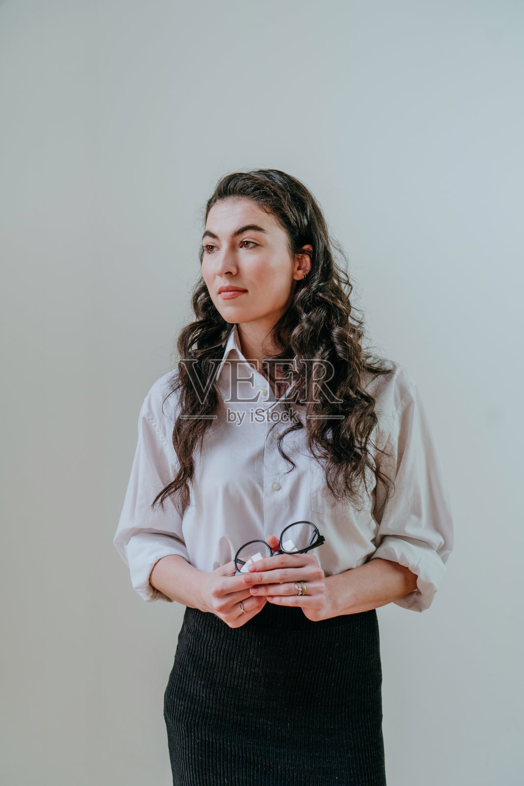 自信的年轻女商人站在灯光墙附近的肖像照片摄影图片