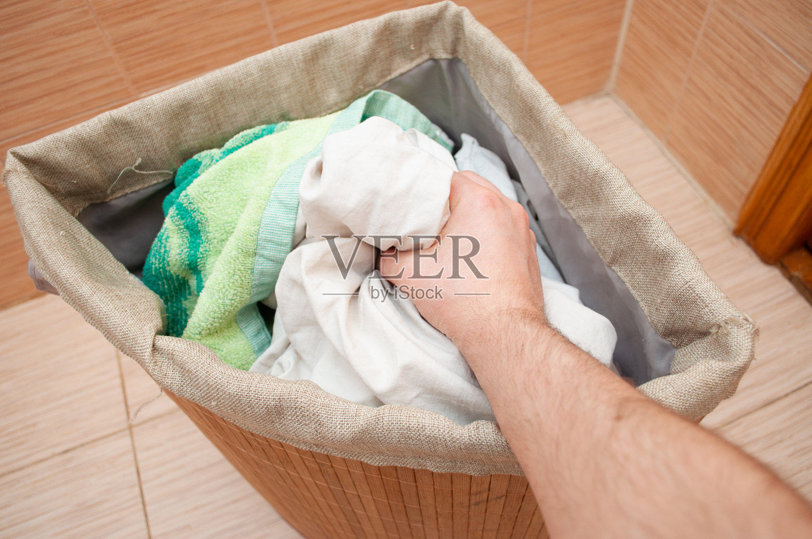 手从洗衣篮里拉出脏衣服照片摄影图片