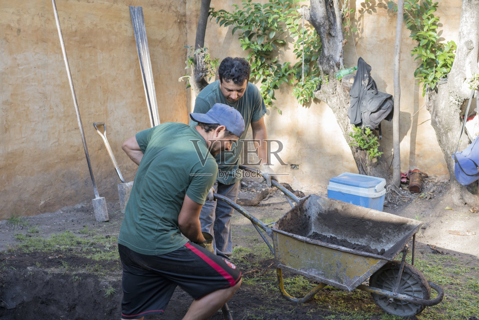 建筑工人在自家后院挖洞照片摄影图片