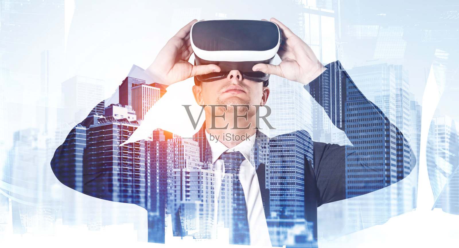 年轻英俊的西装商人拿着VR眼镜。双重曝光，背景是摩天大楼。企业网络连接、通信和虚拟现实和增强现实的概念。照片摄影图片