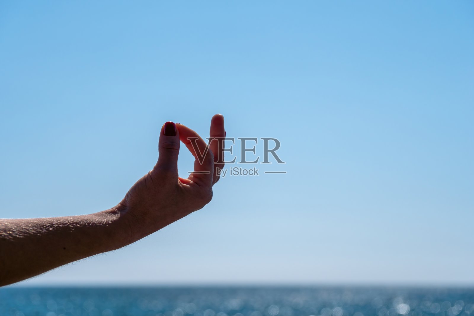 年轻女子长头发，健身教练在运动服紧身裤和上衣，伸展前普拉提，在一个阳光明媚的日子，在海边的瑜伽垫上，女性健身瑜伽常规概念照片摄影图片