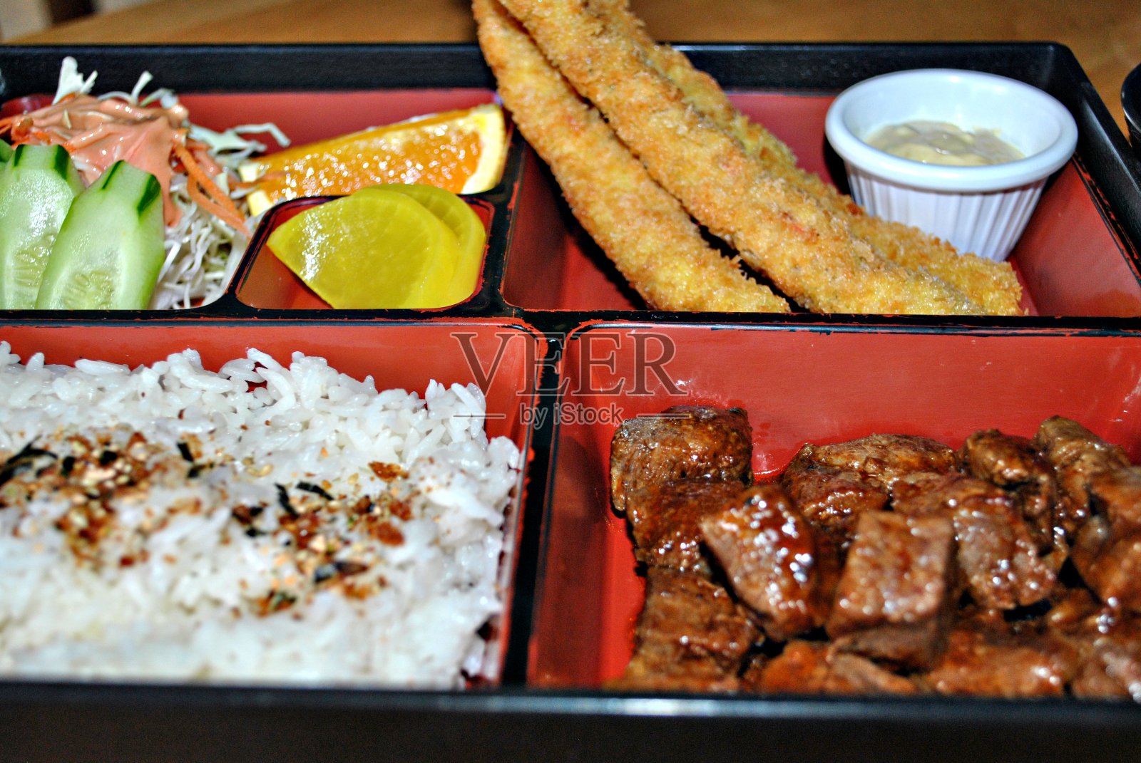 传统的日本便当，有部分的芝麻饭，面包鱼，蔬菜沙拉牛肉块。照片摄影图片