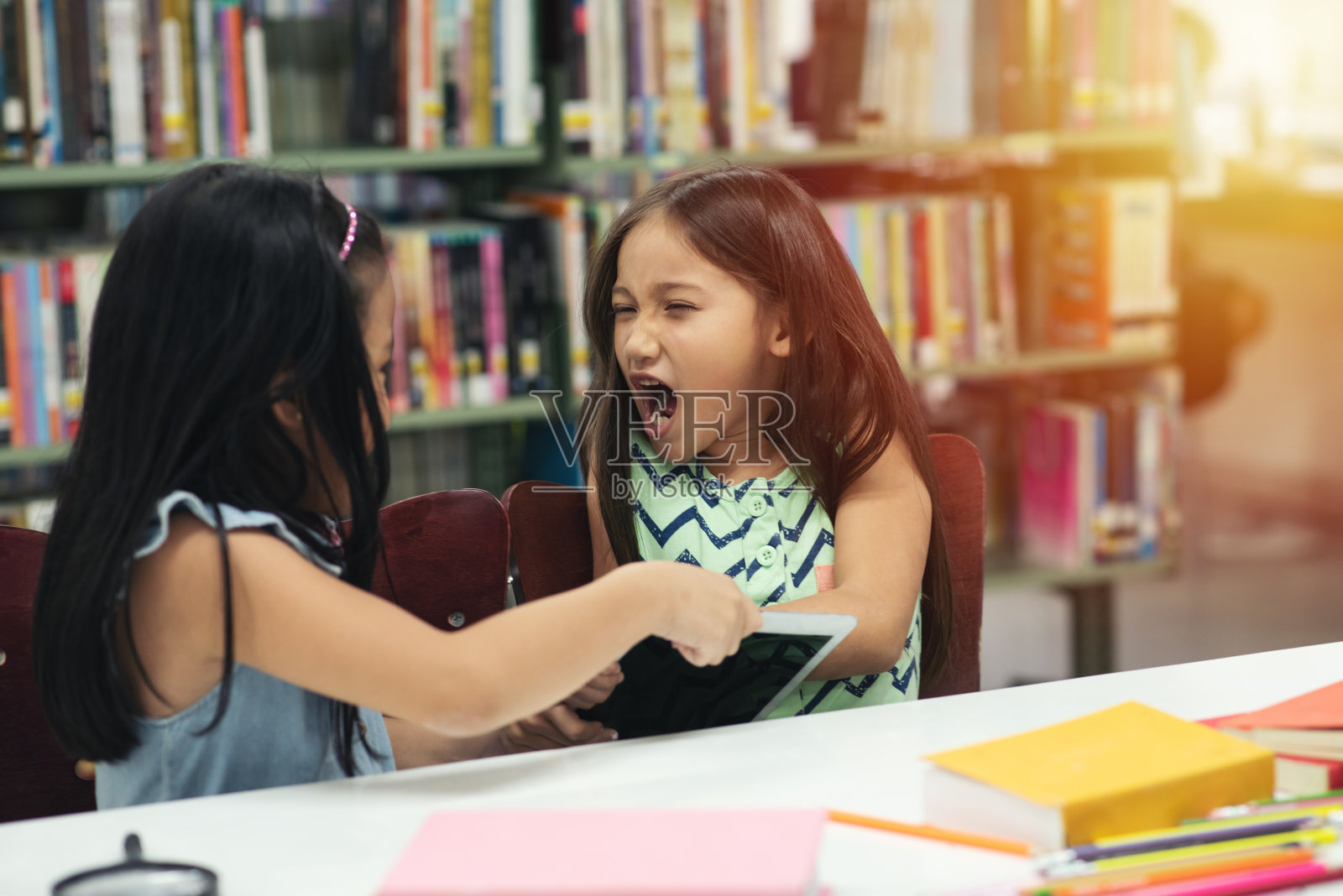 想从朋友手里抢平板电脑的女孩照片摄影图片