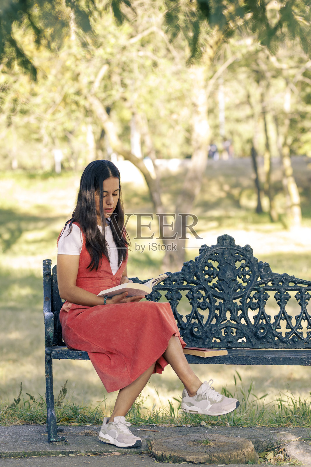 女孩在公园里看书，坐在公园的长椅上，在户外照片摄影图片