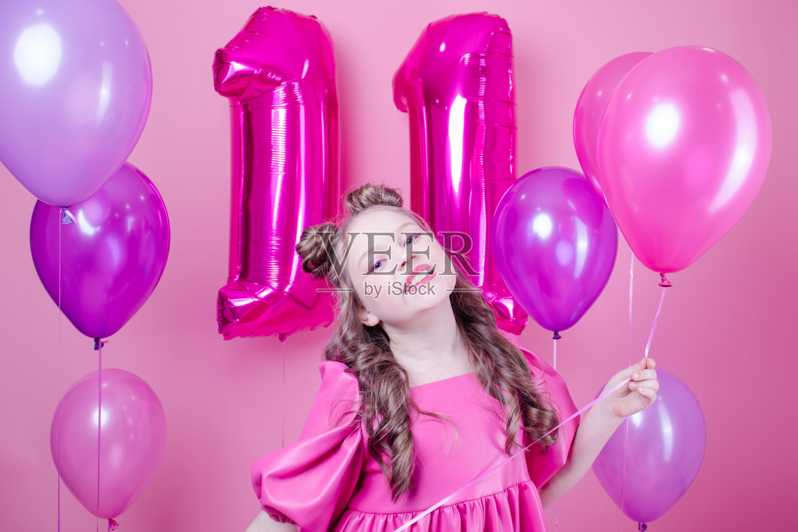 迷人的黑发女孩模型粉红色的化妆和在粉红色的皮衣附近彩色气球在粉红色的背景。欢乐的概念，聚会，生日。照片摄影图片