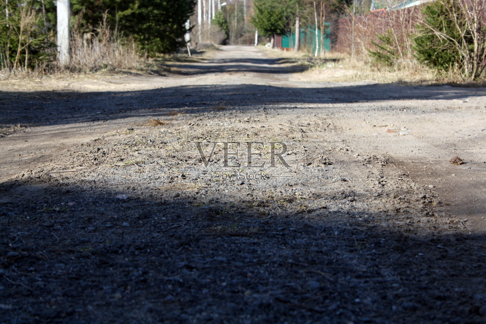 这条路沿着花园的房子。园艺中的土路。一条穿过树林的小路。照片摄影图片