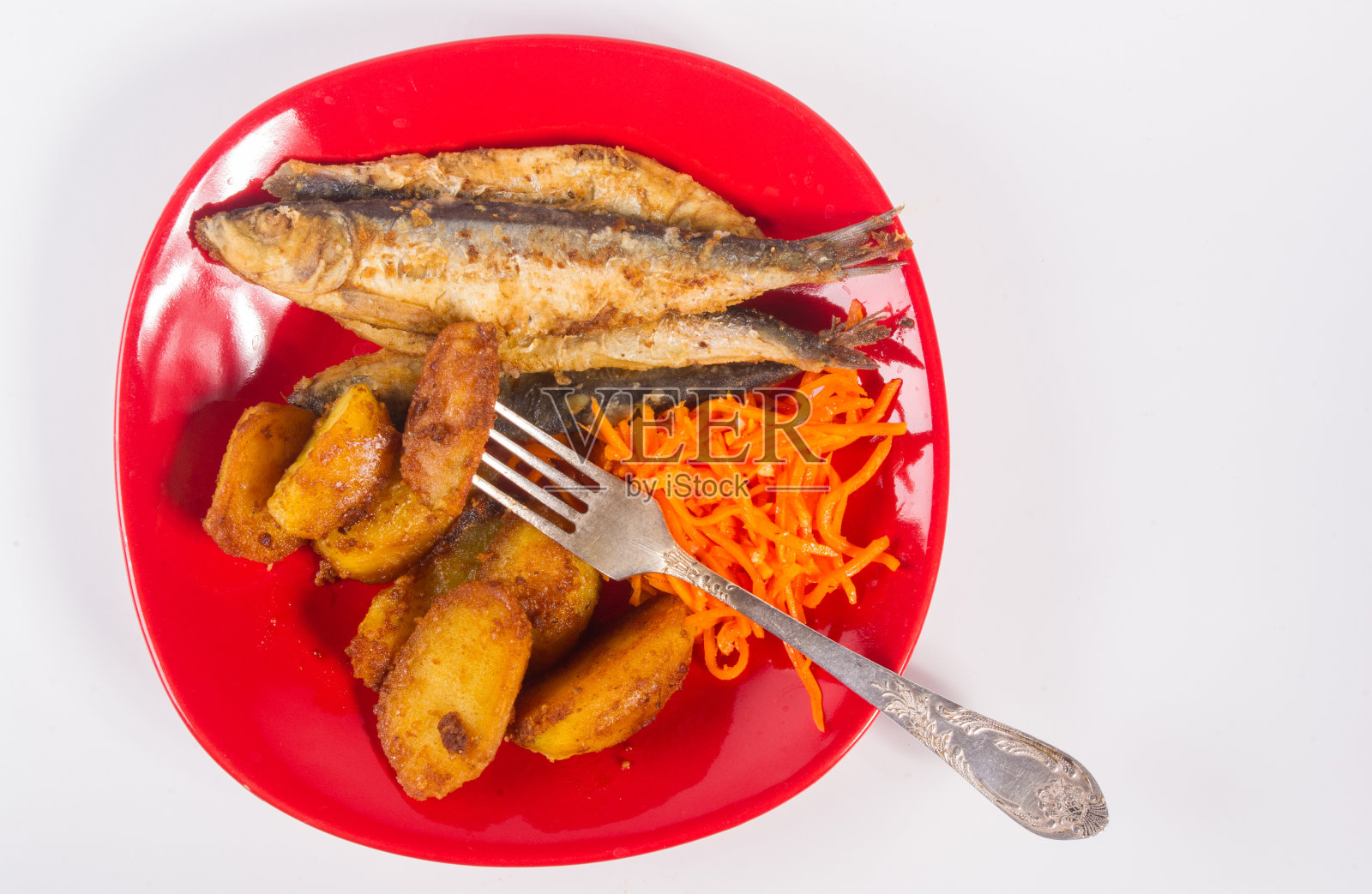 自制菜肴——红色盘子上的炸土豆块、小鱼和腌胡萝卜，简单的乡村食物，特写。照片摄影图片