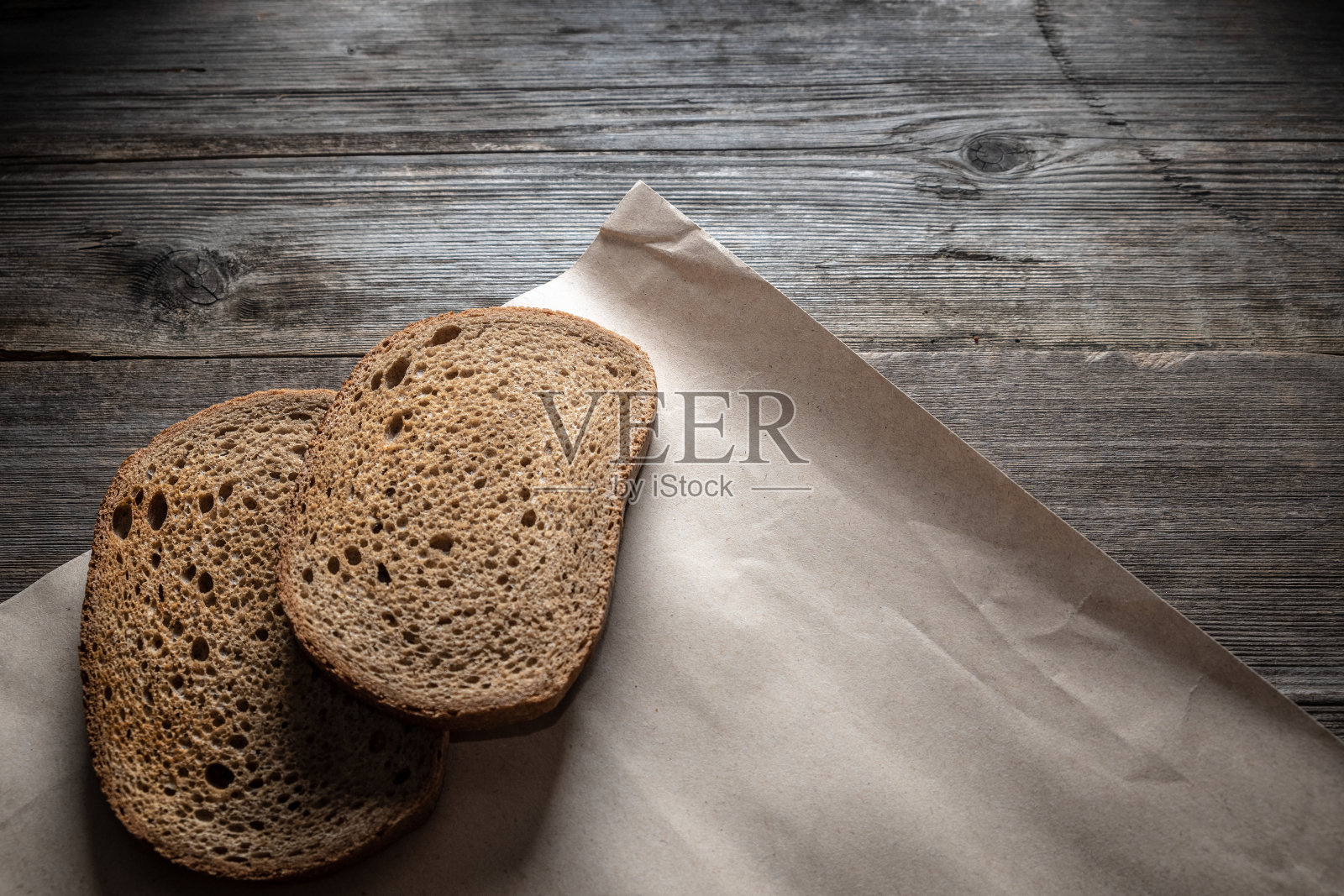 旧木桌上放着两片黑麦面包。简单的乡村静物生活。照片摄影图片