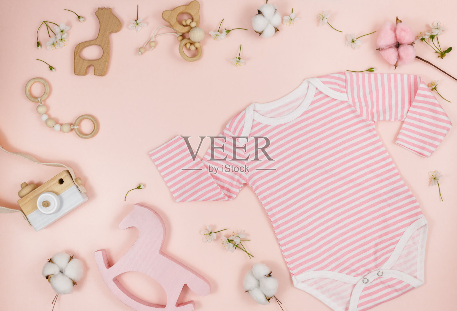 粉红色的桌子上放着新生男孩的粉色紧身衣、小熊和配件。有机棉婴儿紧身衣模型与环保木制玩具。宝宝送礼会，节日，生日装饰。俯视图照片摄影图片