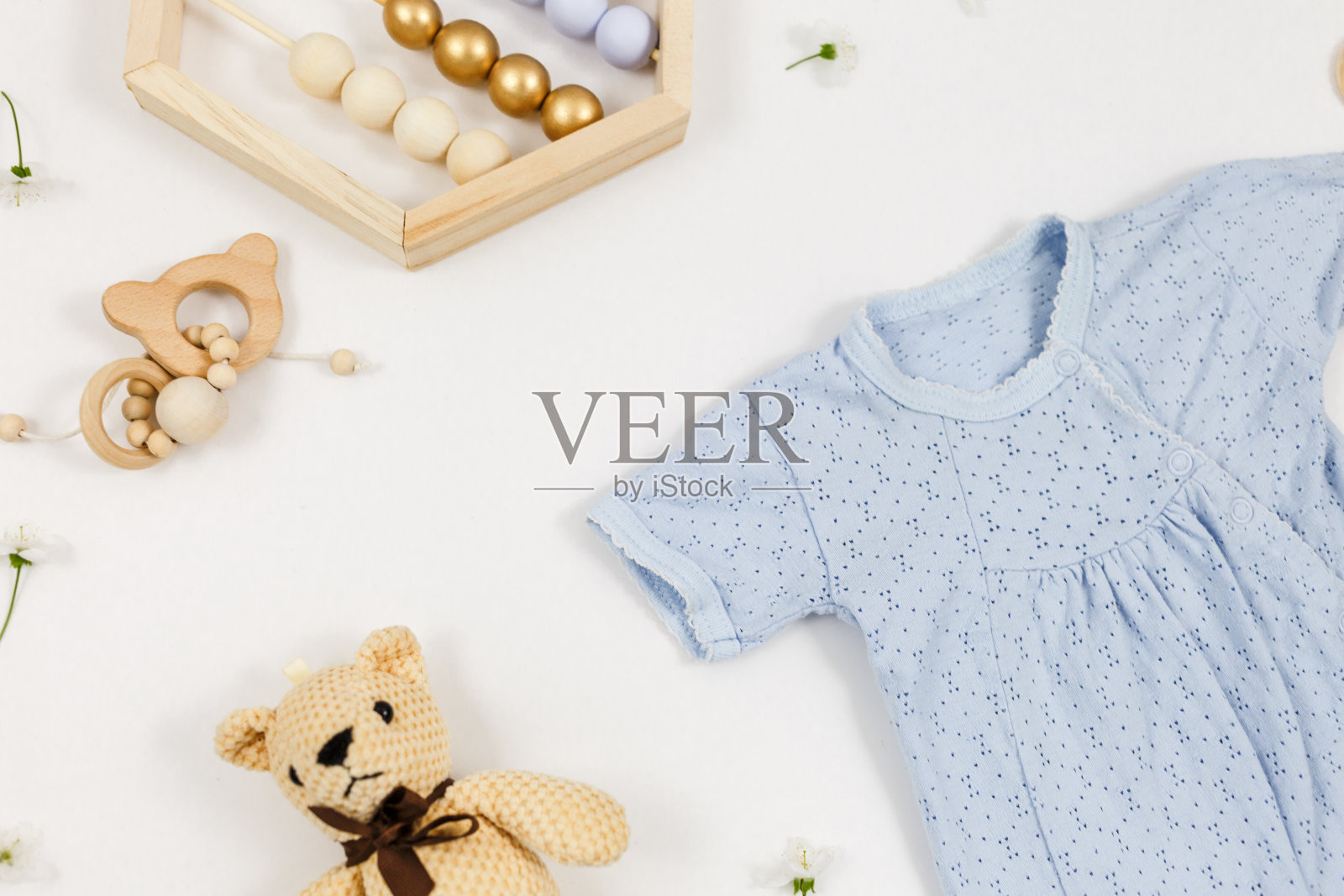 白色的桌子上，蓝色的紧身衣，熊和新生儿的配件。有机棉婴儿紧身衣模型与环保木制玩具。宝宝送礼会，节日，生日装饰。俯视图照片摄影图片