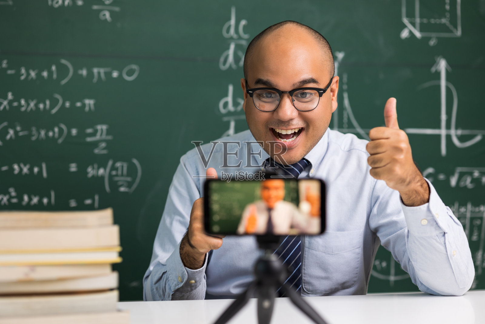 印度年轻教师男子坐着用智能手机进行在线视频会议直播。亚洲数学教师在线授课，供学生在线学习。照片摄影图片