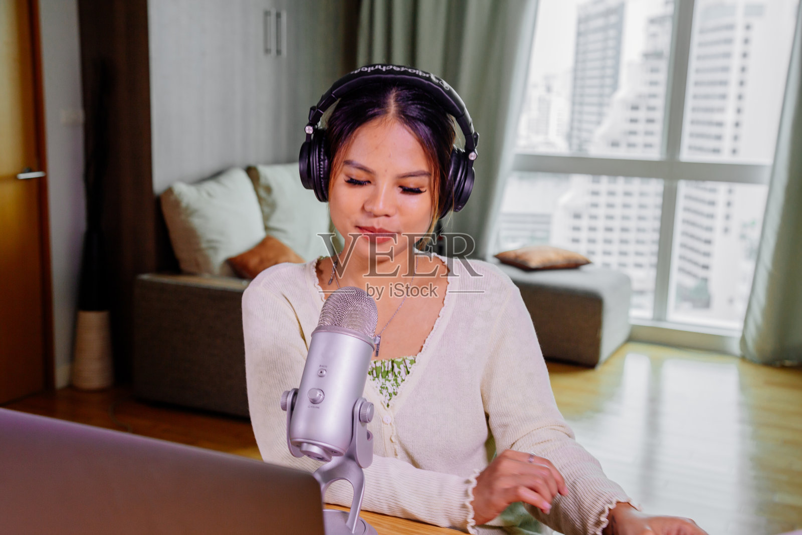 亚洲的博主、播客或视频博主看着摄像机，用技术拍摄视频。社交媒体影响者或内容制造者的概念，在家里放松休闲的风格照片摄影图片