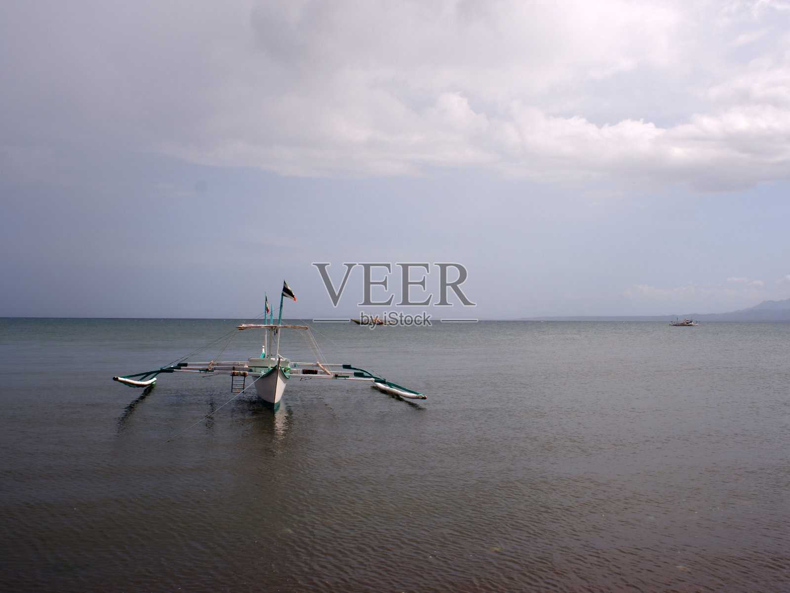 在一个多云的晴天，渔船在海上抛锚停泊。照片摄影图片