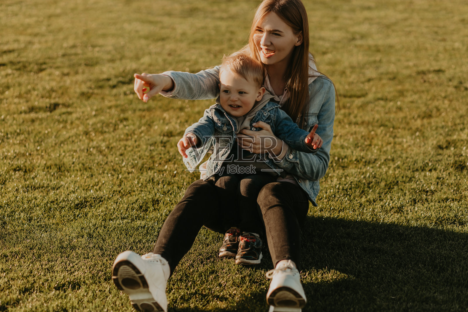 快乐的妈妈和她的宝宝，快乐的宝宝和她的妈妈在日落的操场上玩照片摄影图片