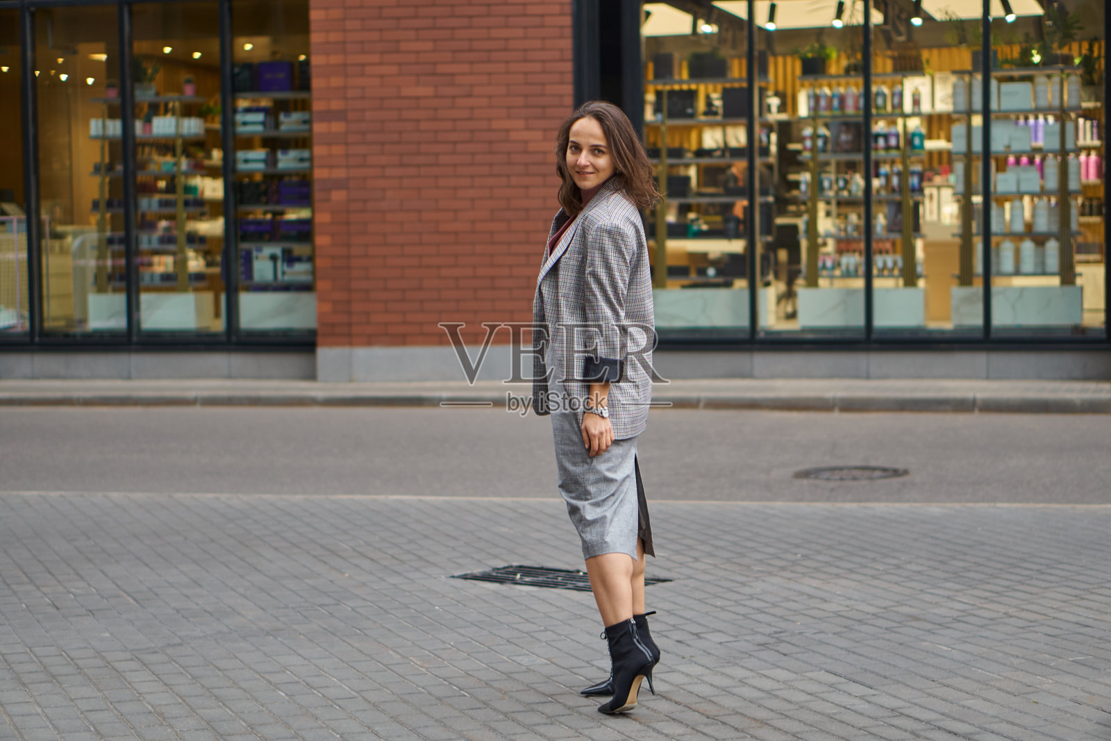 一个穿着灰色连衣裙的女人走在街上。办公室的风格。时尚的头发。照片摄影图片