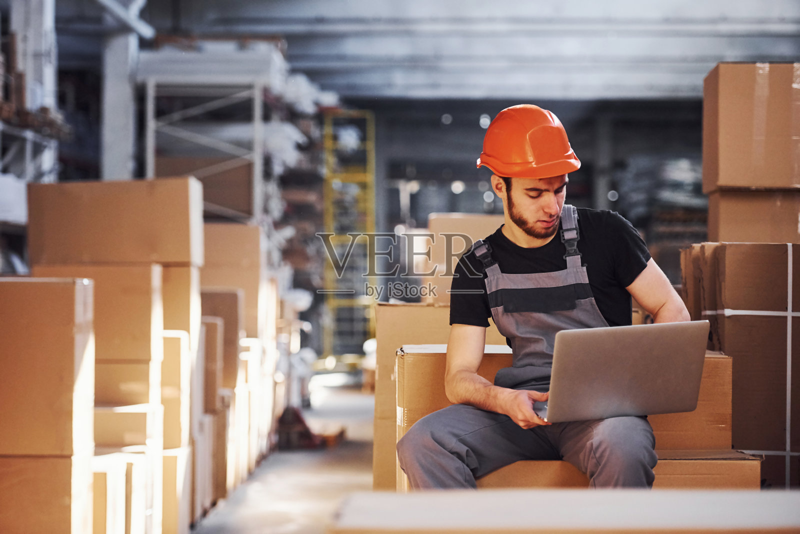身着制服、手持现代笔记本电脑的仓库工人检查生产照片摄影图片