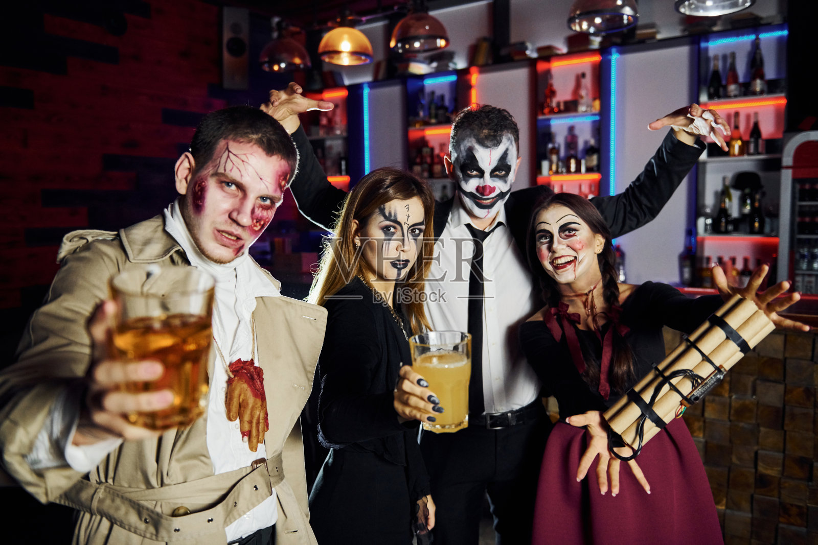 手拿炸弹的朋友们在万圣节主题派对上穿着吓人的化妆和服装照片摄影图片