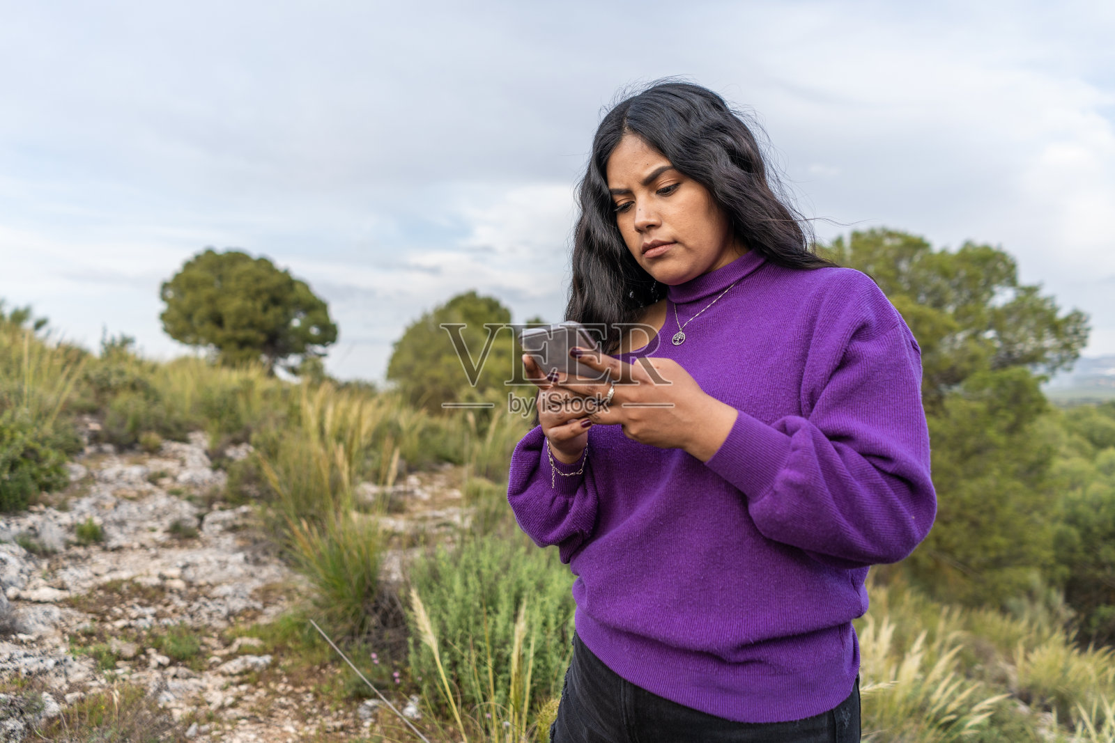 一个在森林里拿着手机的西班牙女人照片摄影图片