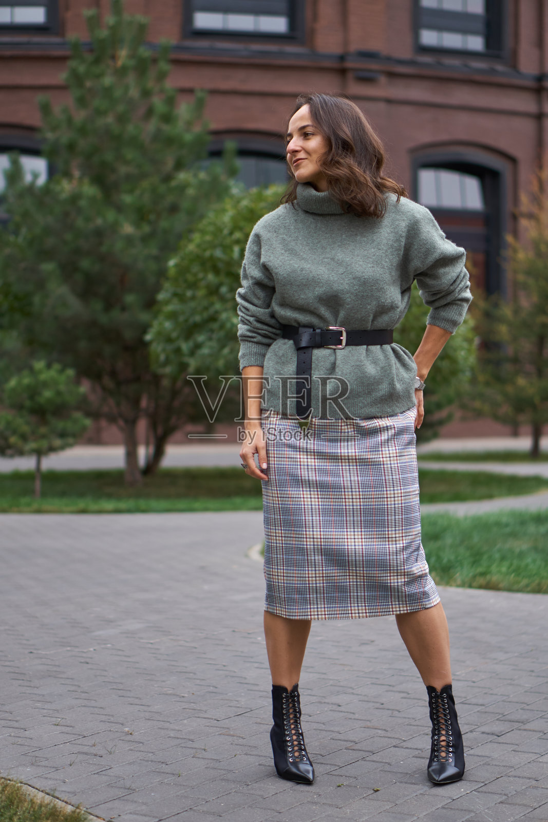 女人穿着时髦。绿色宽松毛衣，黑色腰带，裙子。照片摄影图片