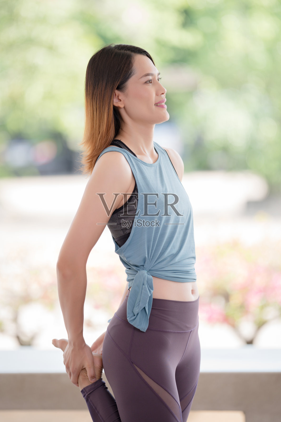 在COVID-19大流行期间，年轻美丽的亚洲女性穿着运动服，在炎热的锻炼前做伸展运动，以保持健康的生活。健康的年轻女子伸展运动和热身运动照片摄影图片