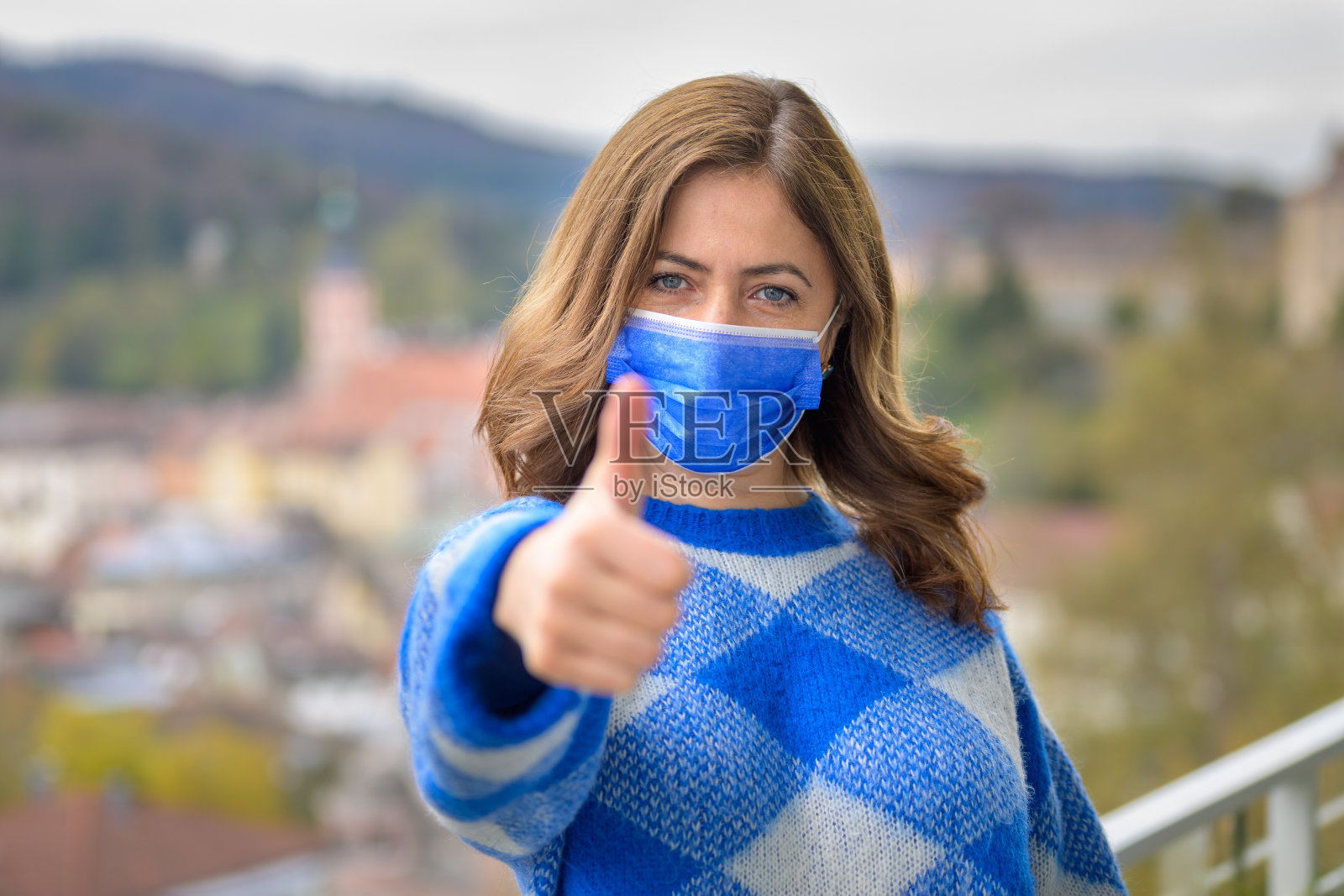 积极的女人戴着面罩，竖起大拇指照片摄影图片