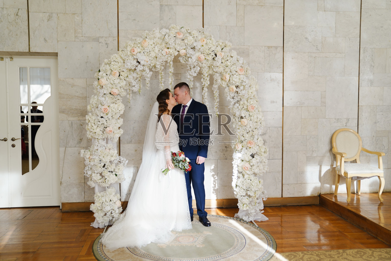 美丽而幸福的新娘和新郎在婚礼上花的拱门照片摄影图片