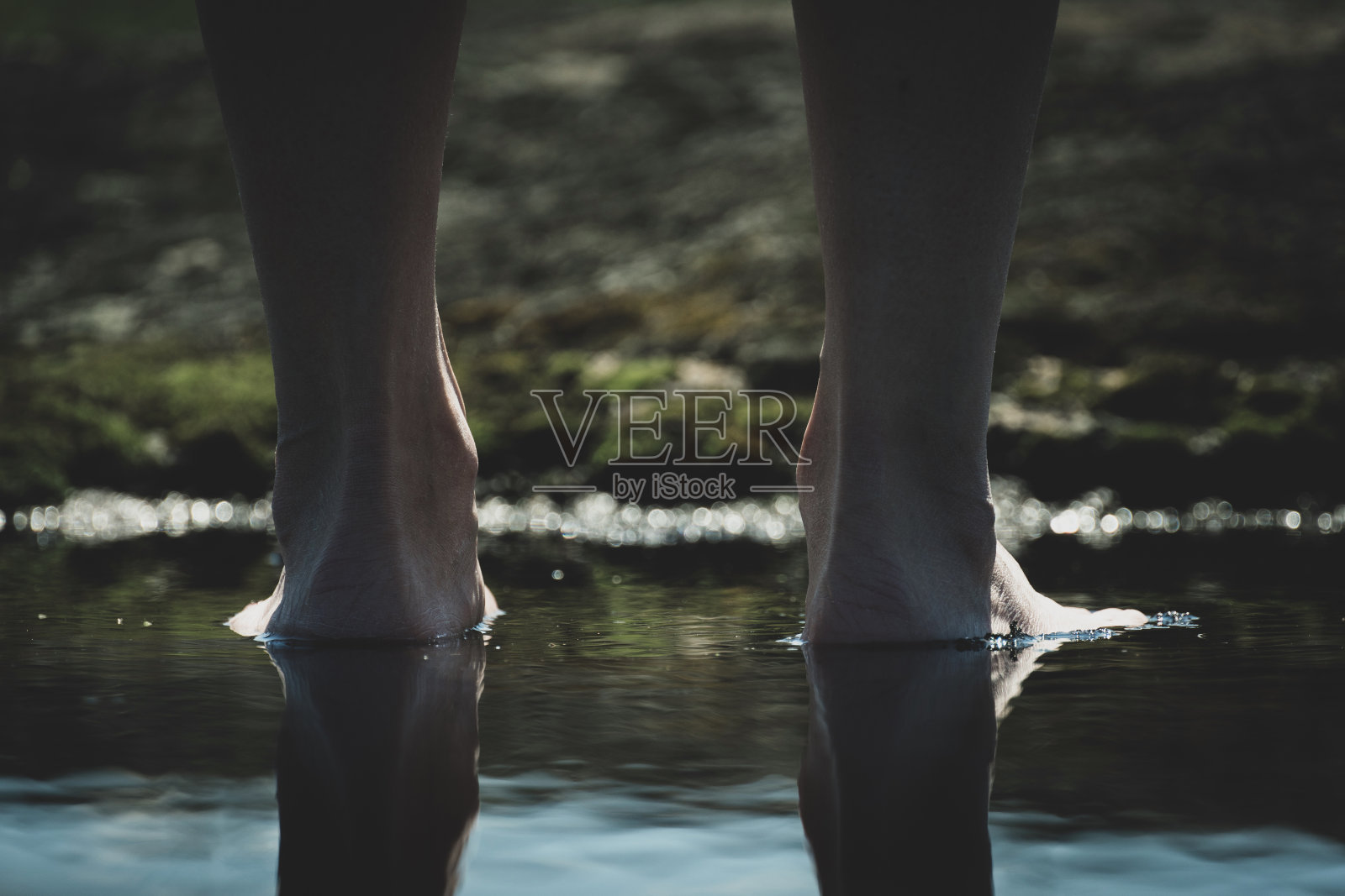 光着脚在水坑里。一个女人赤脚走在户外的水坑里。照片摄影图片