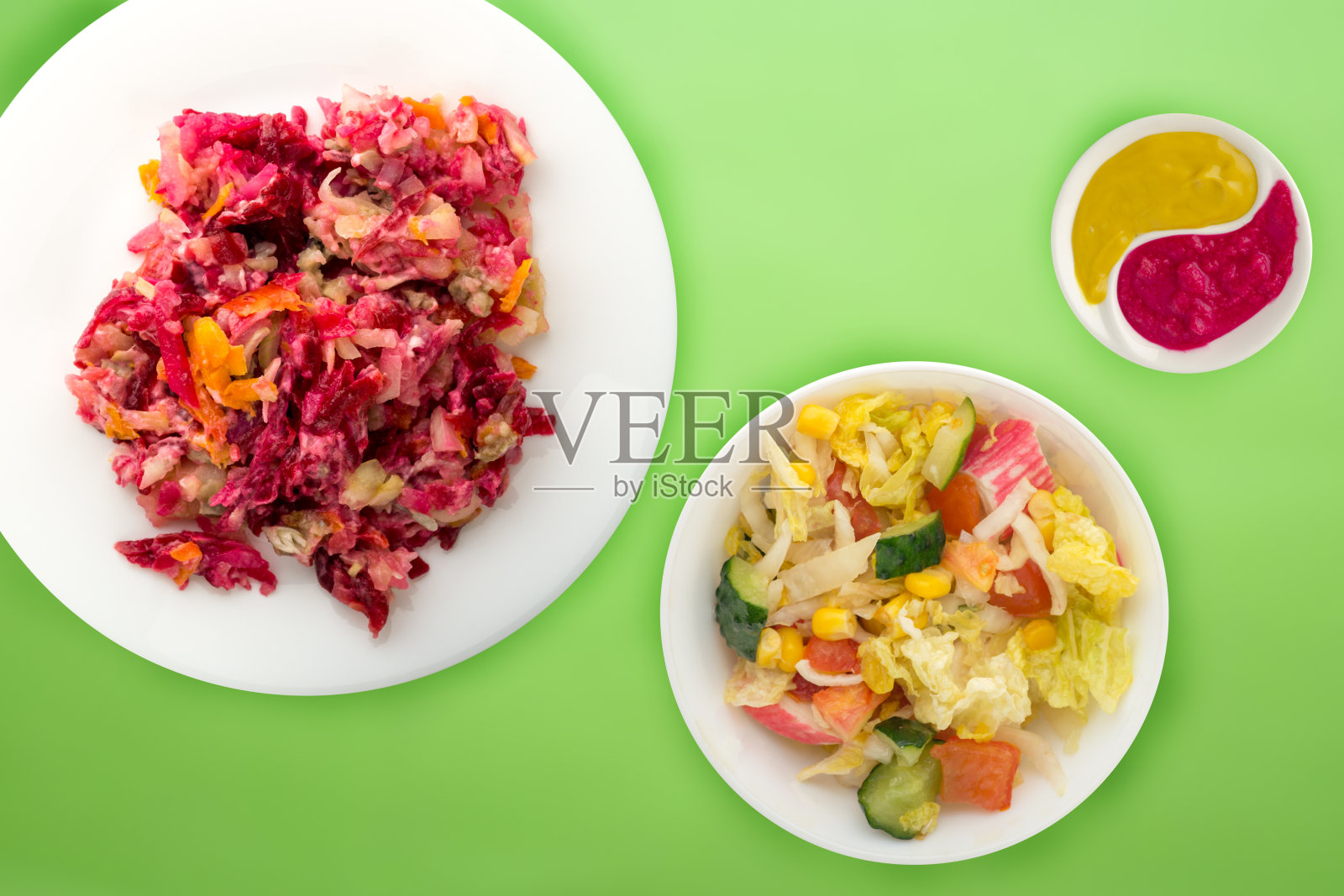 白色盘子里披着毛皮的鲱鱼。有颜色背景的毛皮下的鲱鱼。鲱鱼，甜菜根，胡萝卜，蛋黄酱和洋葱沙拉。照片摄影图片