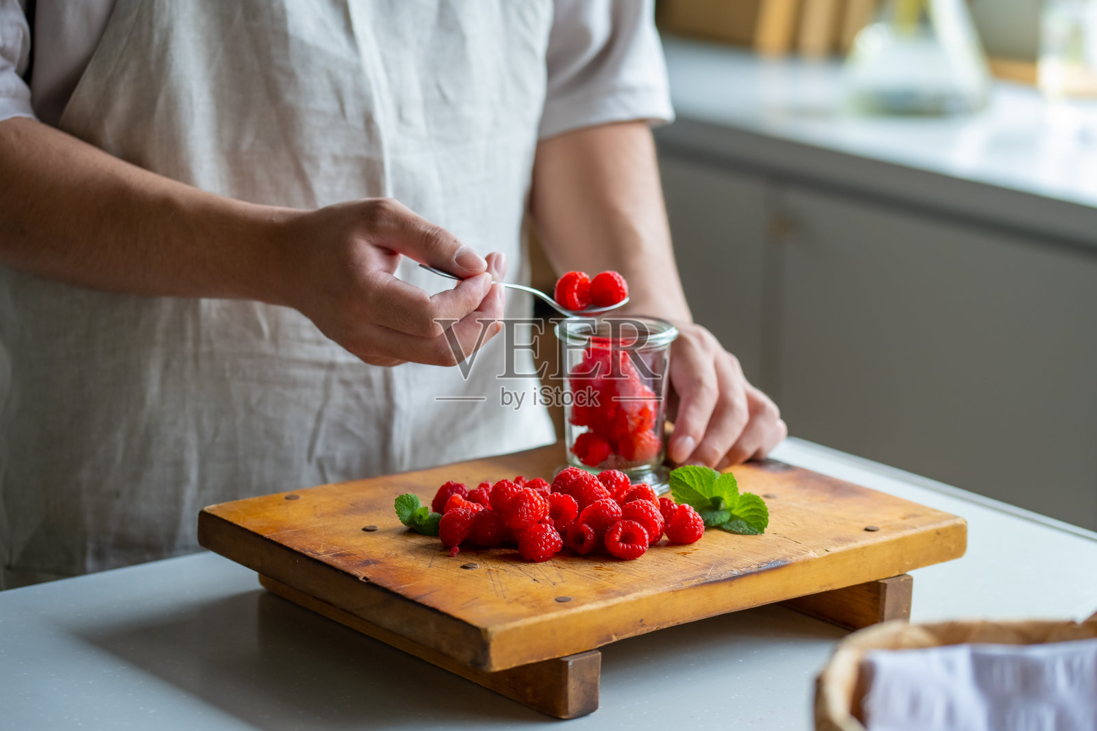 在厨房从罐子里拿覆盆子的男人。照片摄影图片