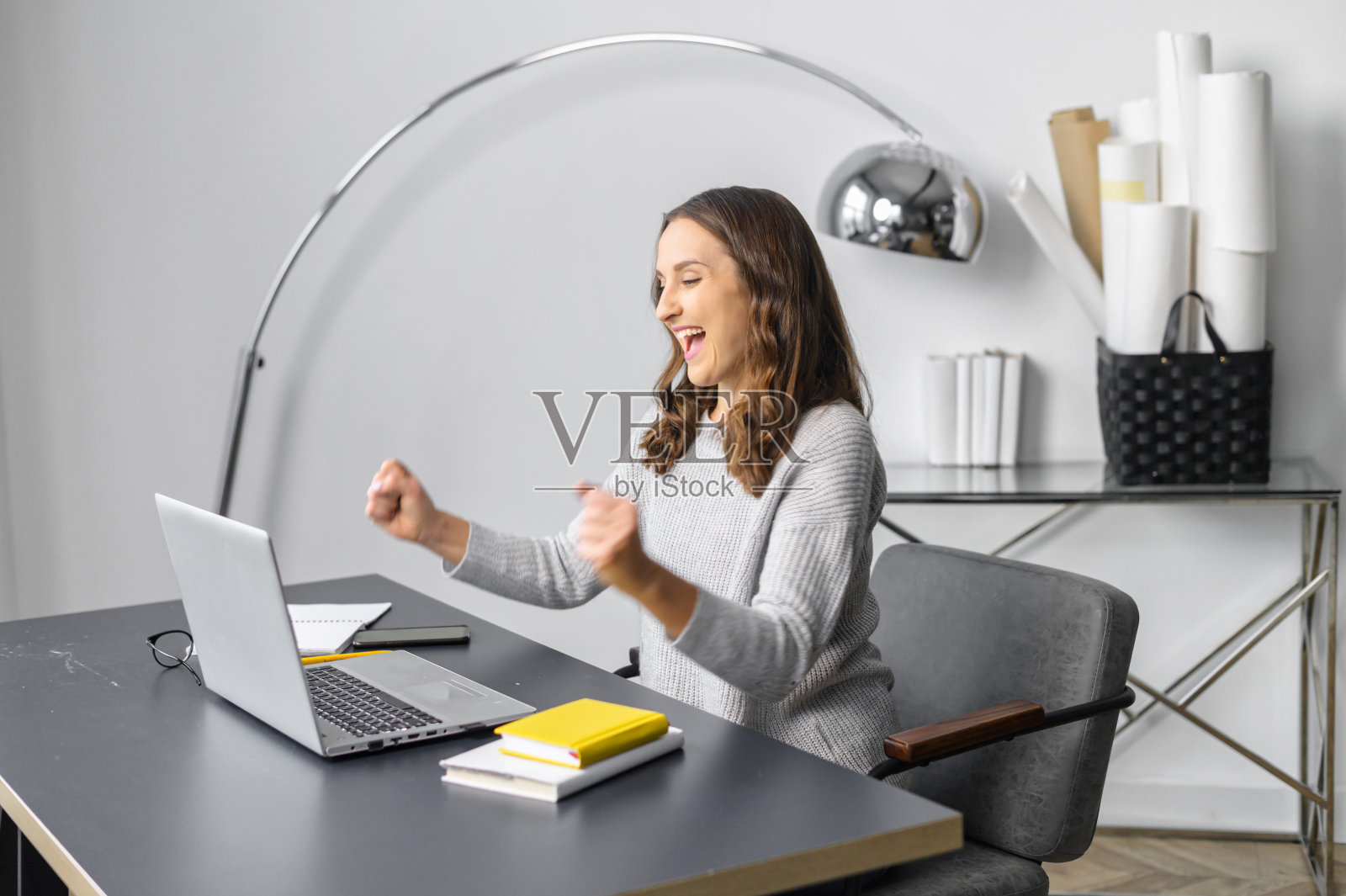 喜出望外的年轻女子惊喜的胜利看着笔记本电脑照片摄影图片