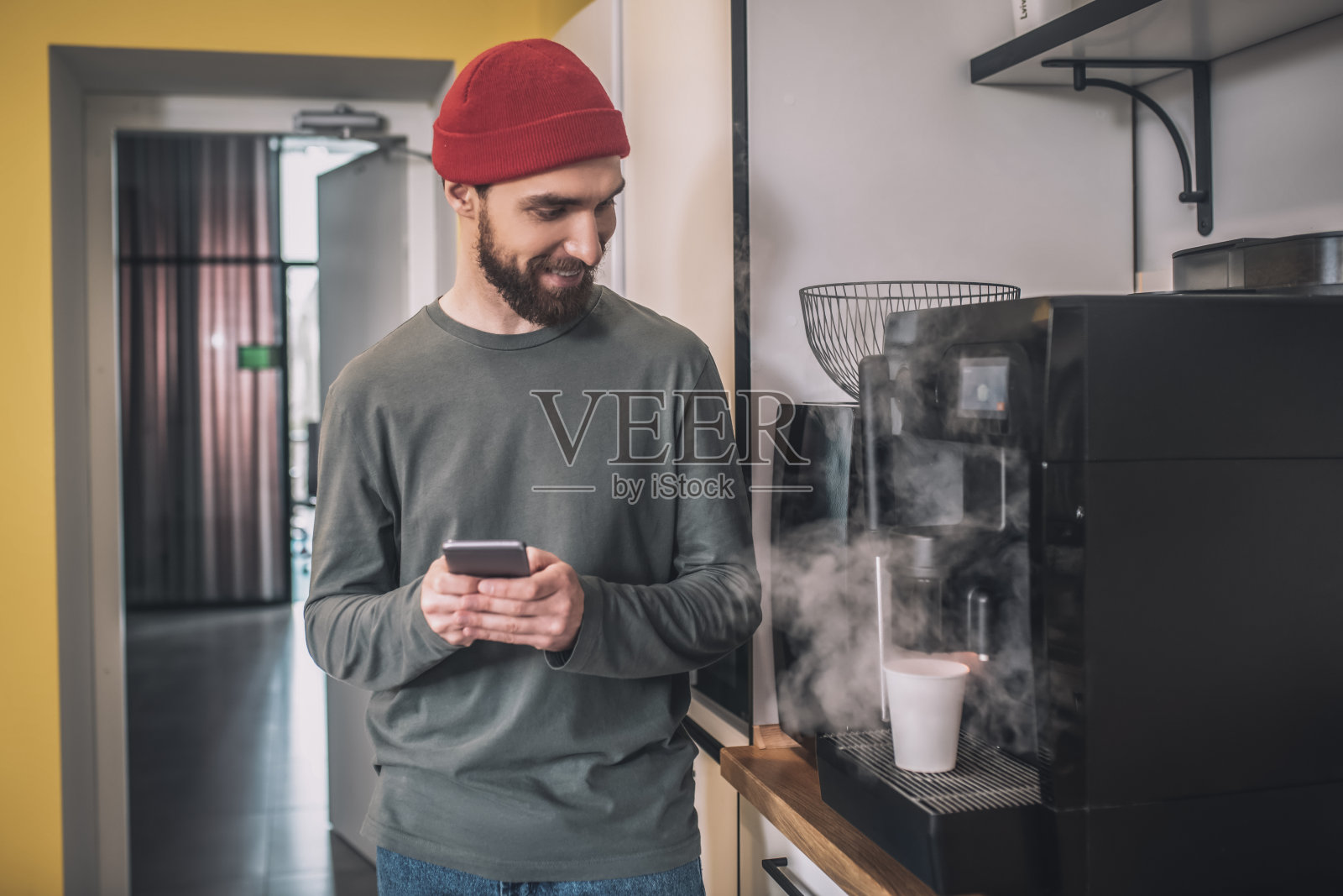 一个戴红帽子的男人站在咖啡机旁边照片摄影图片