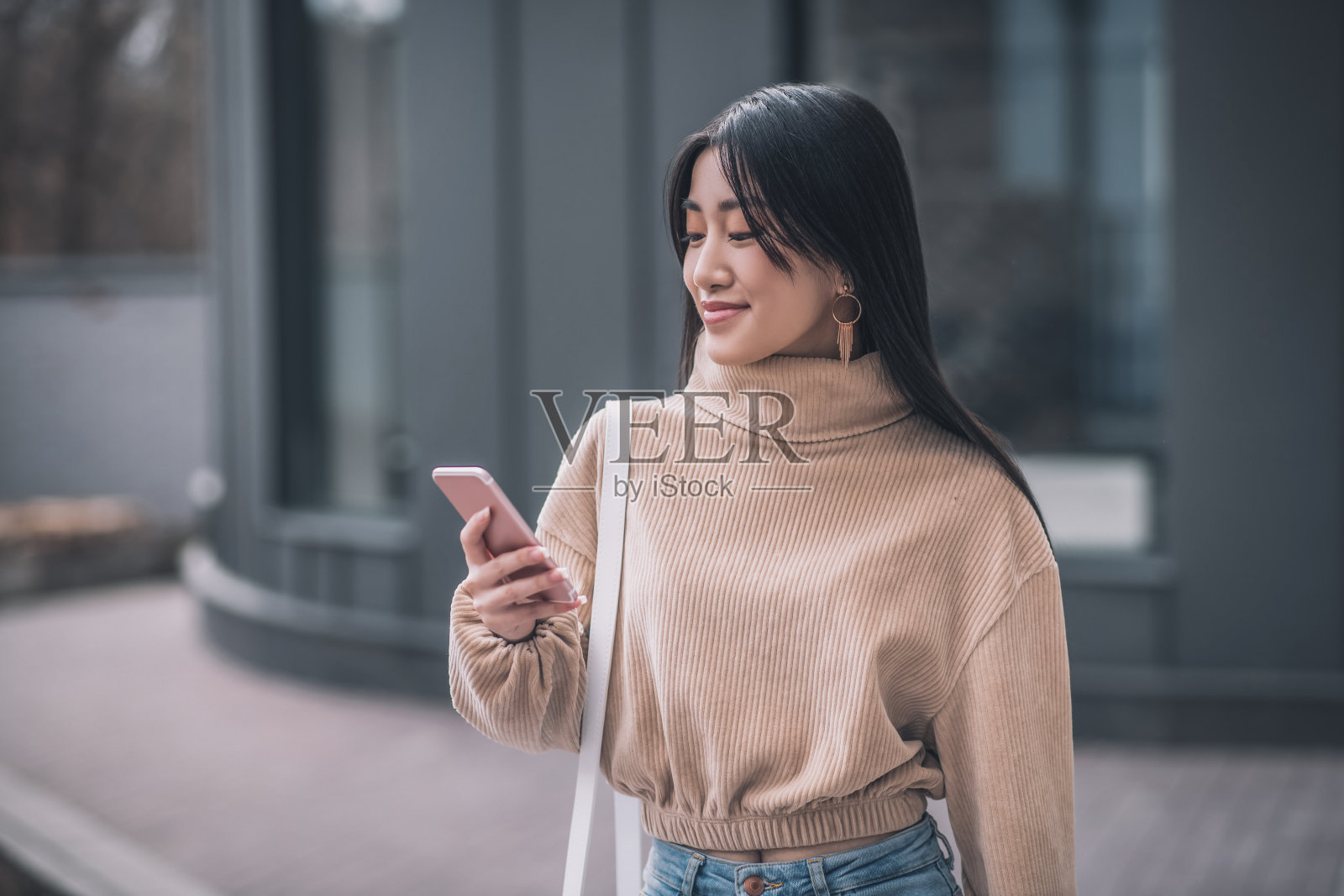 一名拿着智能手机的长发年轻亚洲女性照片摄影图片