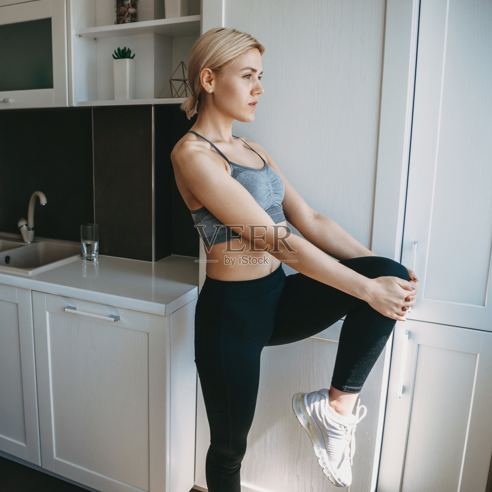 一位金发女郎穿着运动服在厨房里热身照片摄影图片