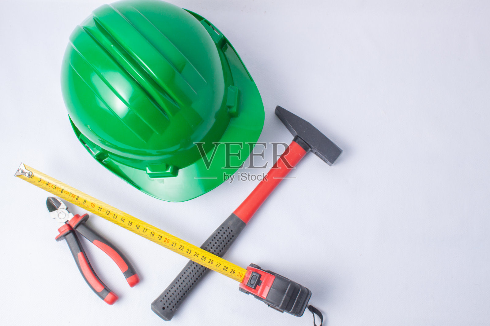 各种工具的概念，如锤子，钳子和仪表加上一个绿色的保护头盔的头部在一个白色的背景。照片摄影图片