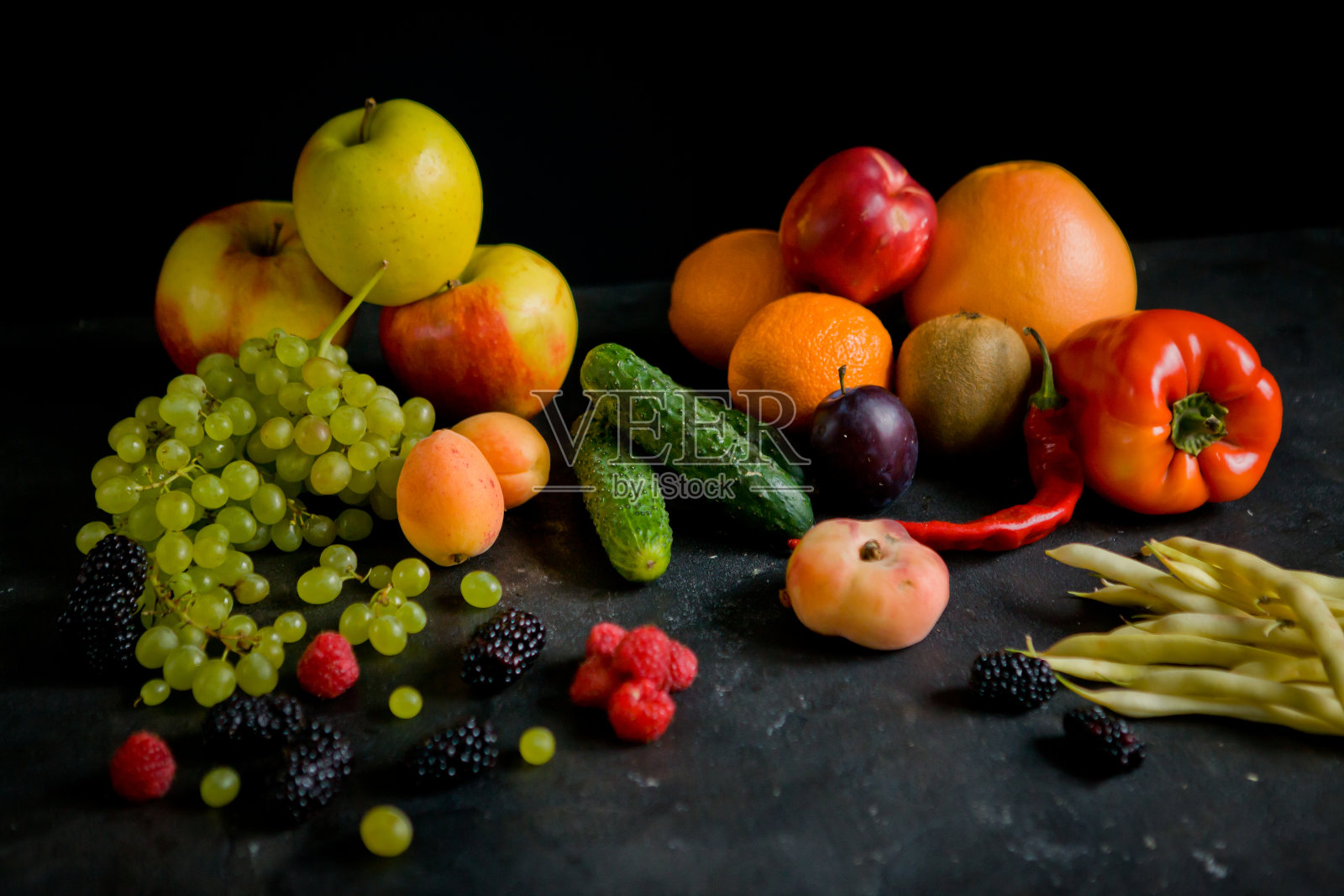 在黑色的背景下，在一张混凝土桌子上，有一个礼盒，里面放着床上的应季蔬菜和水果。一个菜园，一个村庄。照片摄影图片