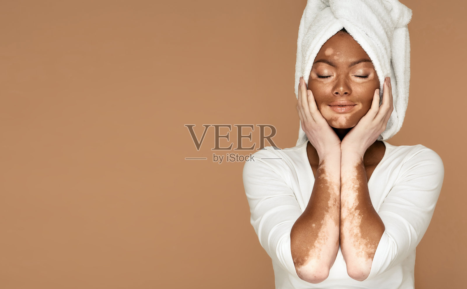 一个白癜风的非洲女人的美丽肖像，毛巾围着她的头。米色背景和文本的位置照片摄影图片