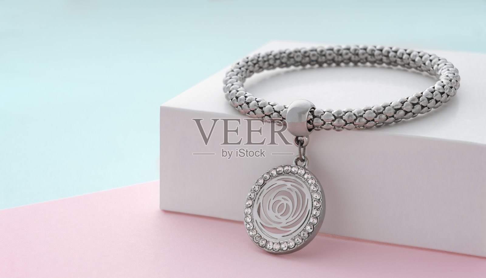 粉彩色背景上的花形银色手链照片摄影图片
