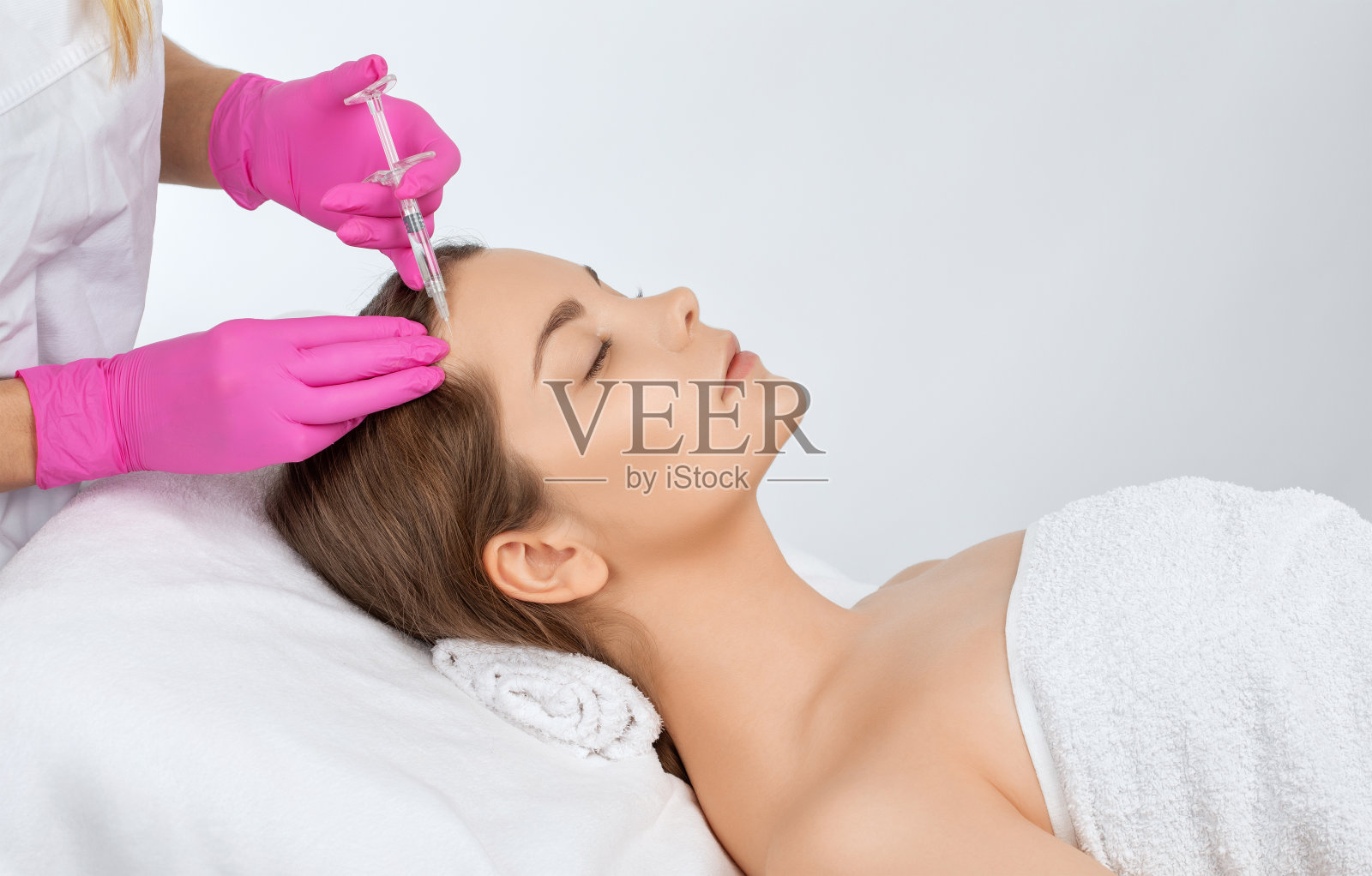 美容师使年轻化抗皱注射在一个美丽的女人的脸上。在美容院做女性美容。照片摄影图片