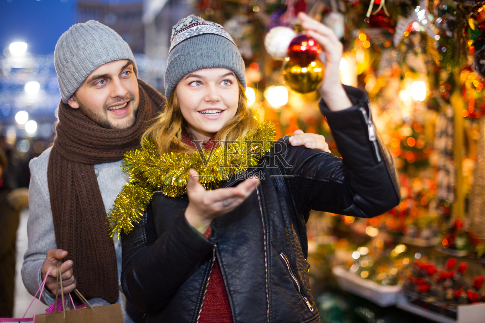 一对快乐的年轻夫妇在集市上拿着圣诞玩具照片摄影图片