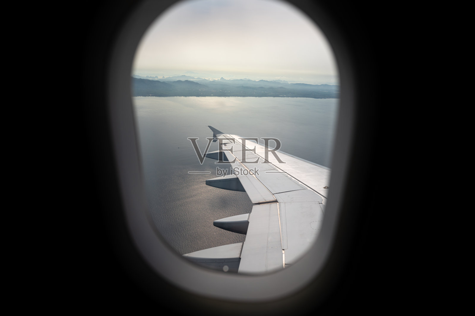 透过以海洋为背景的飞机窗框。照片摄影图片