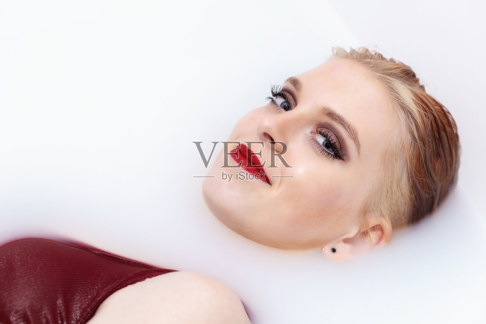 迷人的年轻女子红唇躺在温泉与牛奶对着镜头微笑照片摄影图片