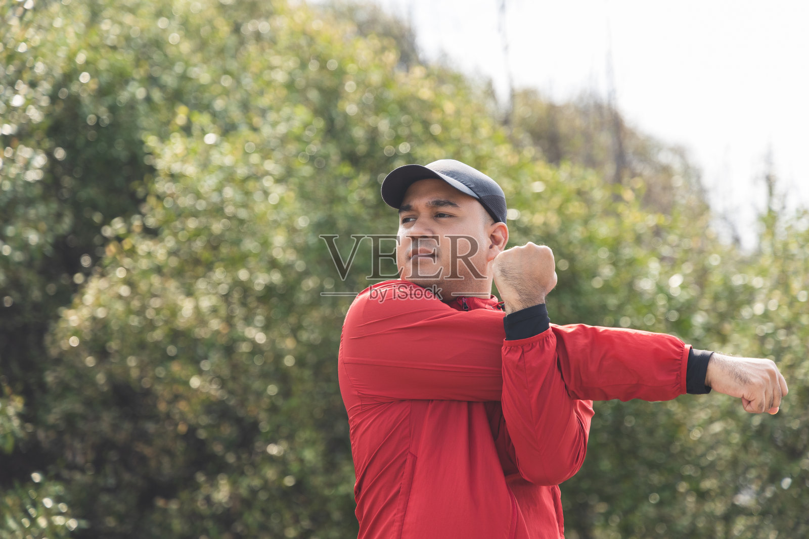 年轻的亚洲男子穿着运动服在户外跑步。印度男子在路上奔跑前伸展手臂的肖像。训练运动员户外运动概念。照片摄影图片