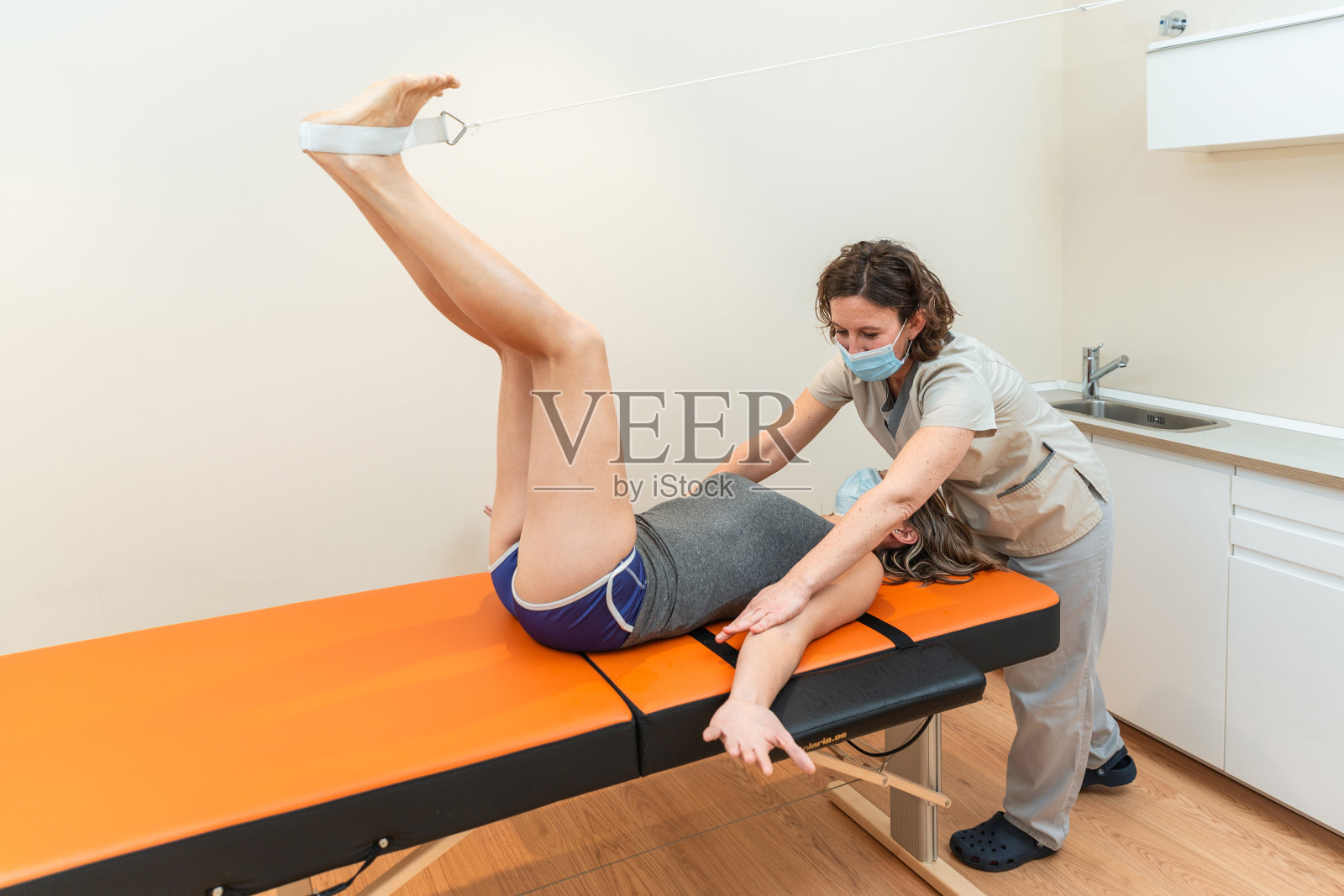 理疗师配合患者，以髋股角闭合姿势伸展照片摄影图片