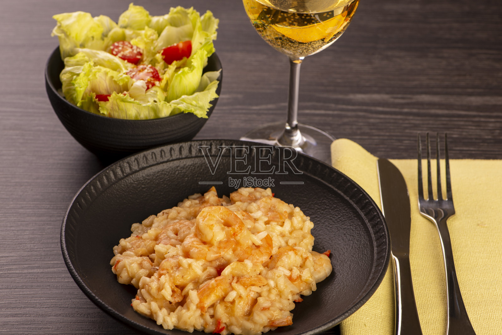 一盘虾仁烩饭，生菜沙拉，圣女果和一杯白葡萄酒照片摄影图片