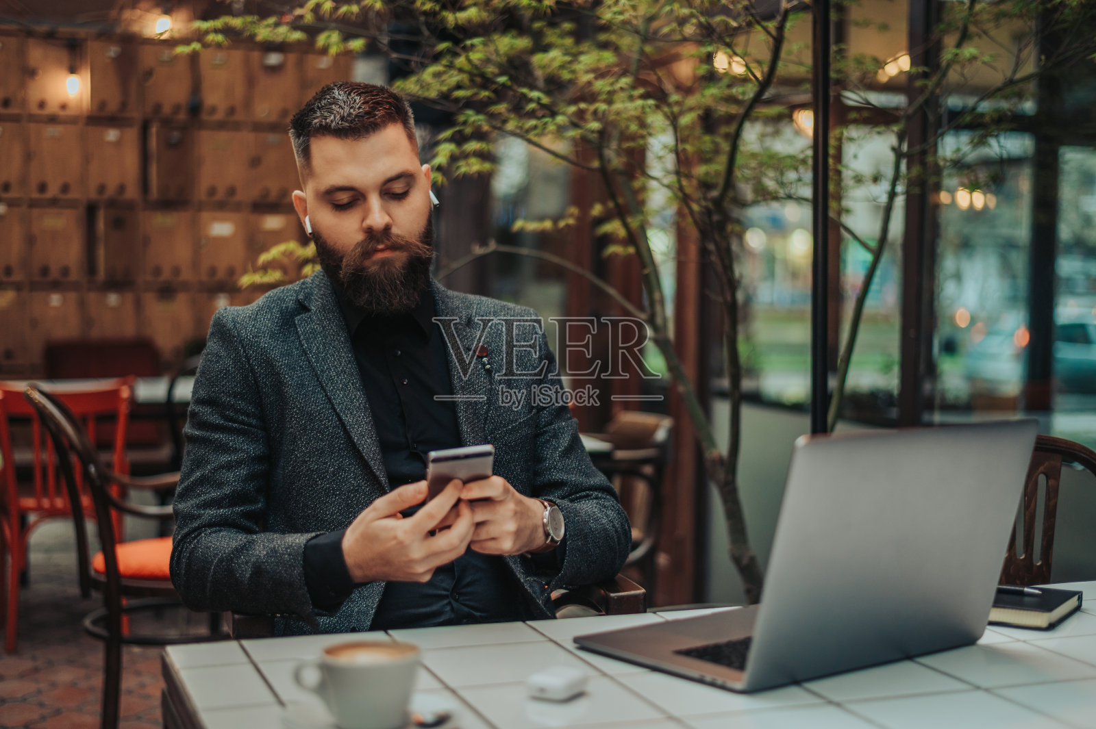 在咖啡馆工作时使用智能手机和笔记本电脑的商人照片摄影图片