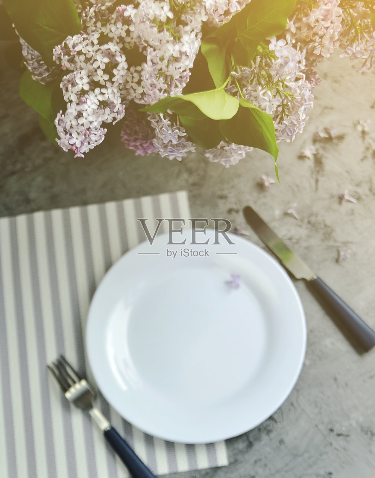 布置桌子。盘子里放着刀叉和丁香花照片摄影图片