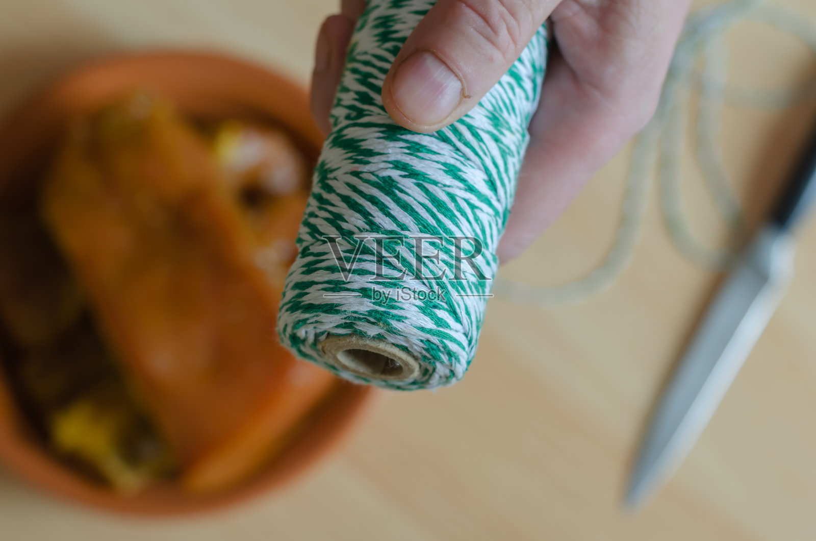 一只手拿着一束白绿相间的麻绳放在厨房的桌子上。照片摄影图片