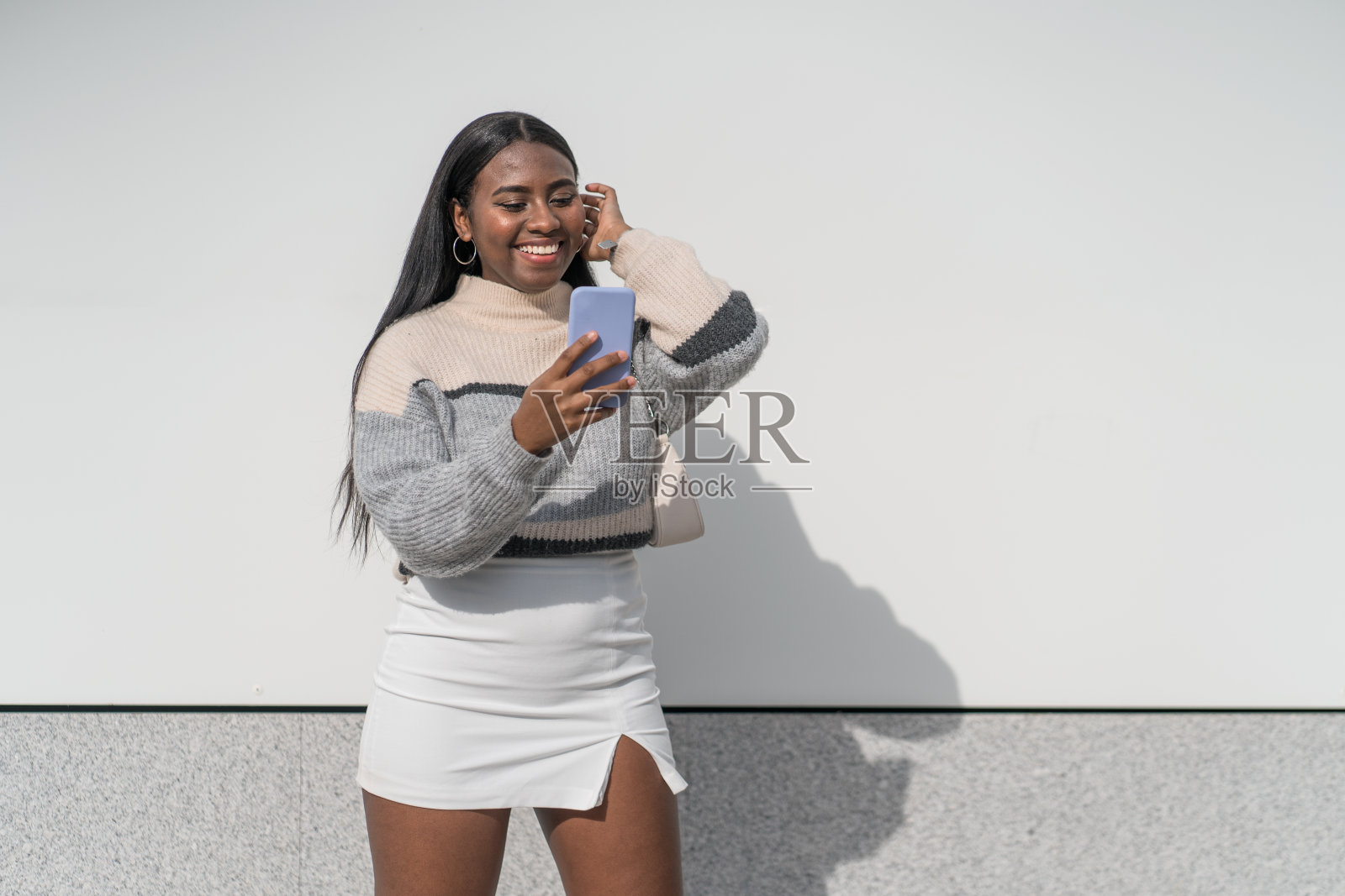 年轻漂亮的黑人女人微笑着看智能手机照片摄影图片
