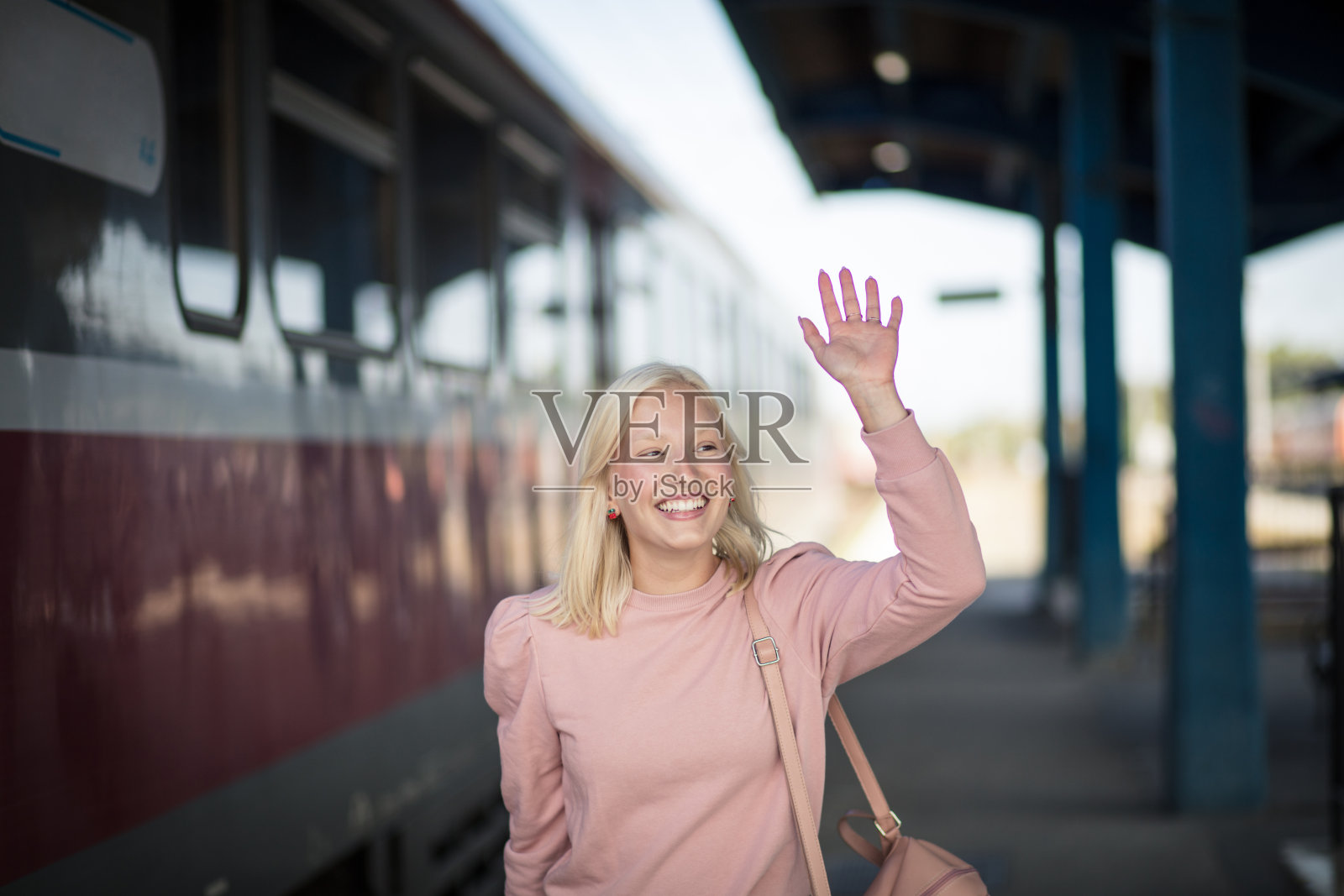 年轻女孩在公共汽车站等公共汽车。照片摄影图片